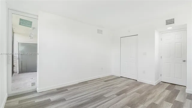 an empty room with wooden floor and mirror