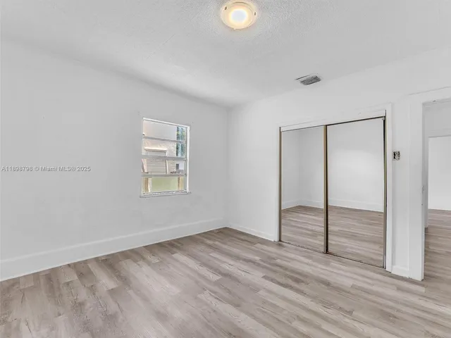 an empty room with wooden floor and window