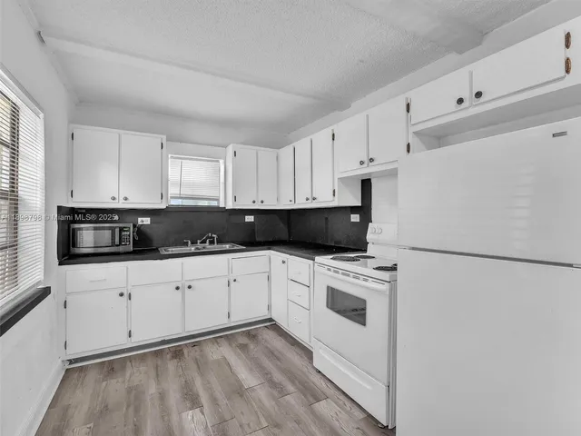 a kitchen with granite countertop white cabinets and white appliances