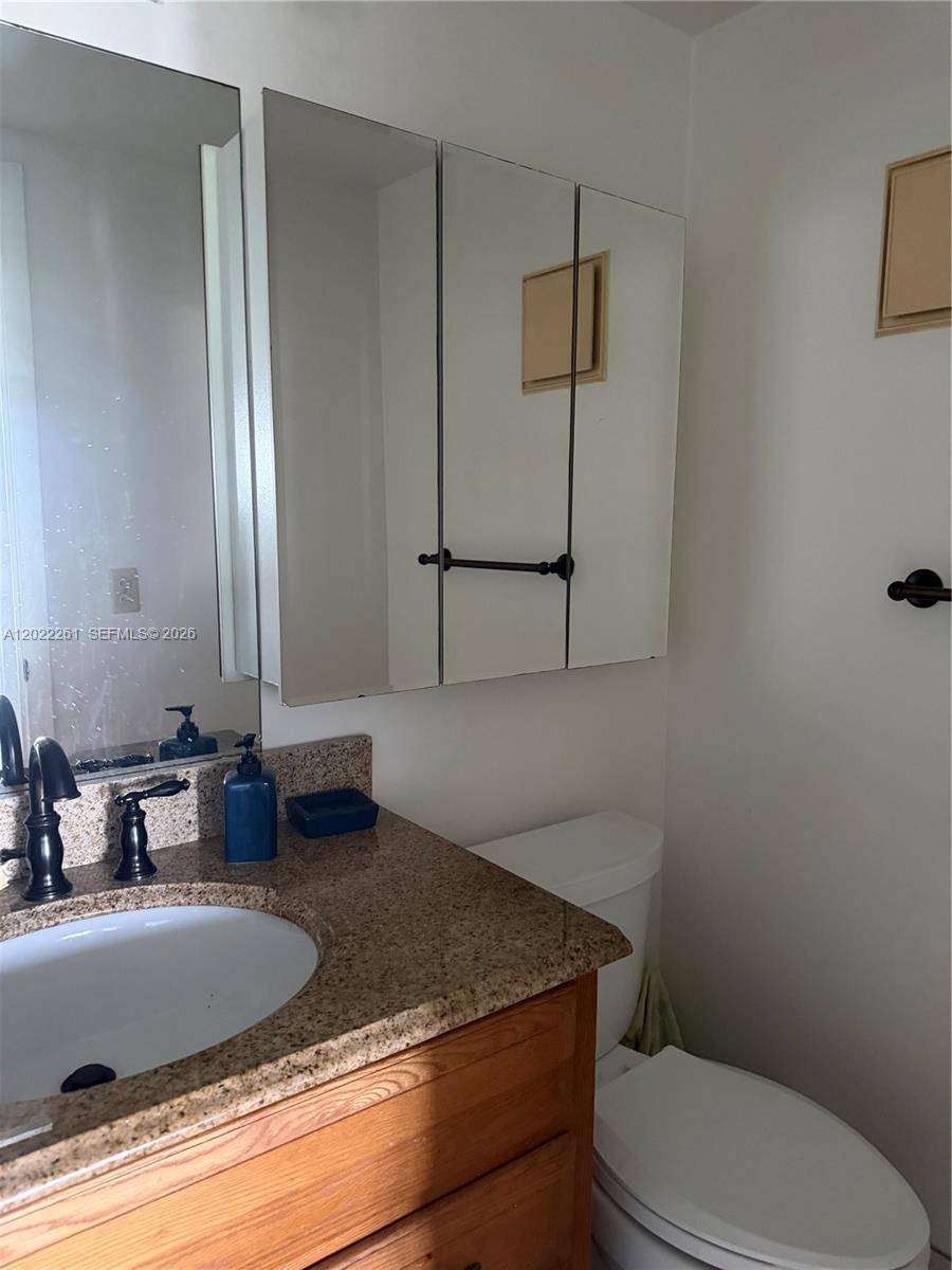 4043 Cornwall C, Unit 4043 Boca Raton, FL 33434 - Photo 6 of 16 a bathroom with a granite countertop sink a mirror and toilet