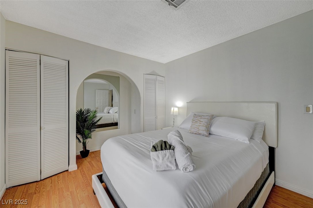 5248 Rambling Road Las Vegas, NV 89120 - Photo 14 of 33 Bedroom featuring multiple closets, light wood-style flooring, and a textured ceiling