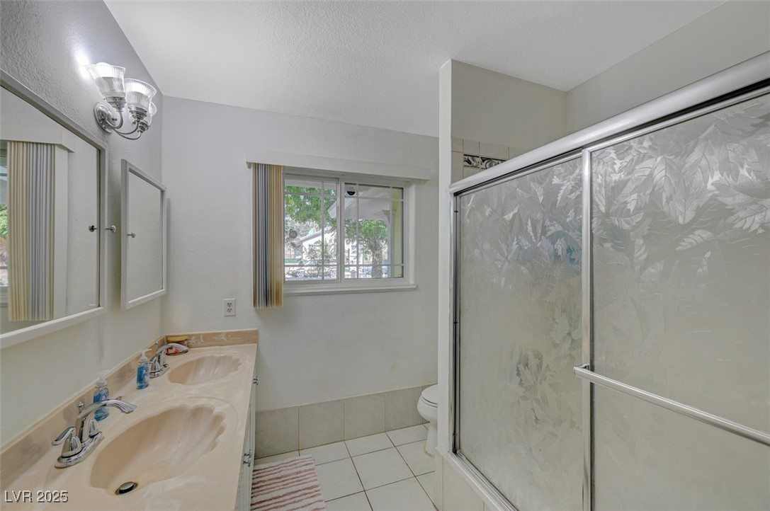 5248 Rambling Road Las Vegas, NV 89120 - Photo 20 of 33 Bathroom featuring light tile patterned floors, a shower stall, double vanity, and a textured ceiling