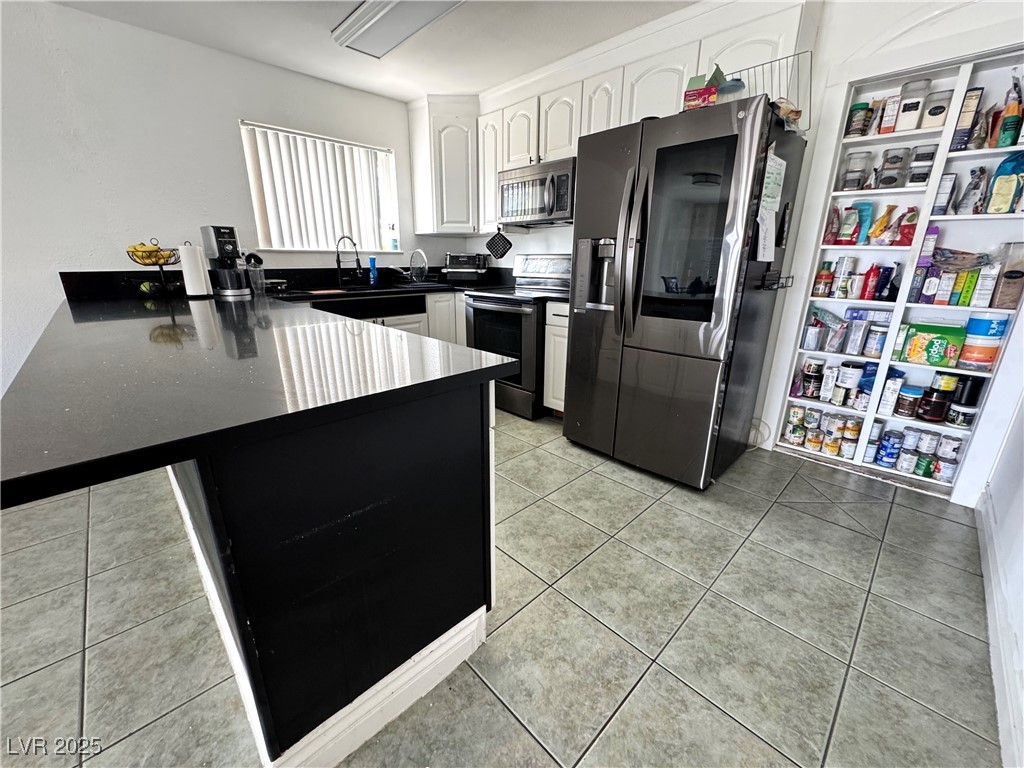 5248 Rambling Road Las Vegas, NV 89120 - Photo 6 of 33 Kitchen with appliances with stainless steel finishes, light tile patterned floors, a peninsula, white cabinets, and a breakfast bar area