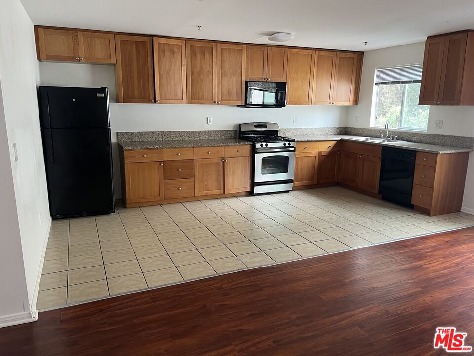 a kitchen with stainless steel appliances kitchen island granite countertop wooden floors a stove top oven a sink and dishwasher