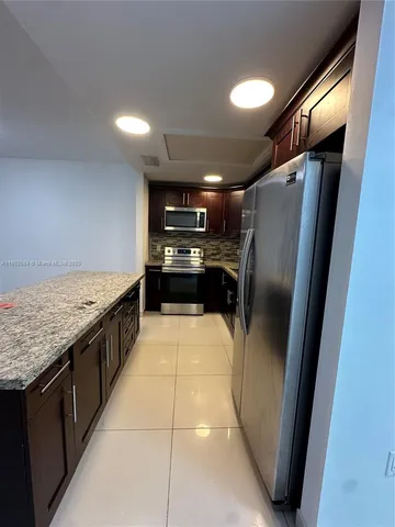 a kitchen with stainless steel appliances granite countertop a refrigerator a sink and a stove