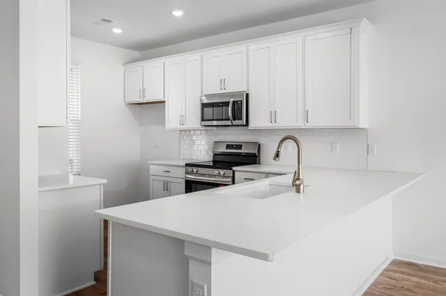 a kitchen with stainless steel appliances a sink a stove a microwave a sink a refrigerator and cabinets