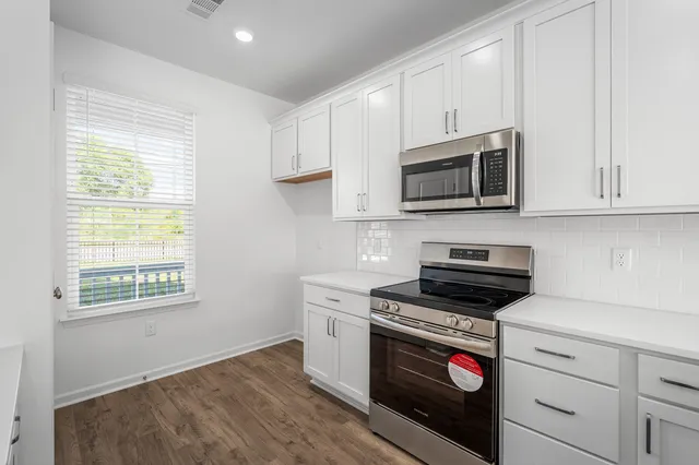 a kitchen with granite countertop white cabinets appliances and a window