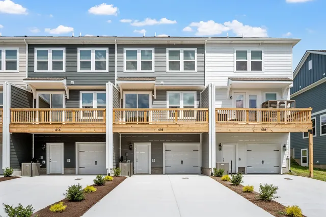 a front view of a building with lot of cars and trees
