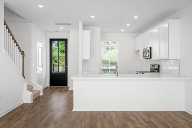 a view of kitchen with stainless steel appliances granite countertop a refrigerator a sink and a stove with wooden floor