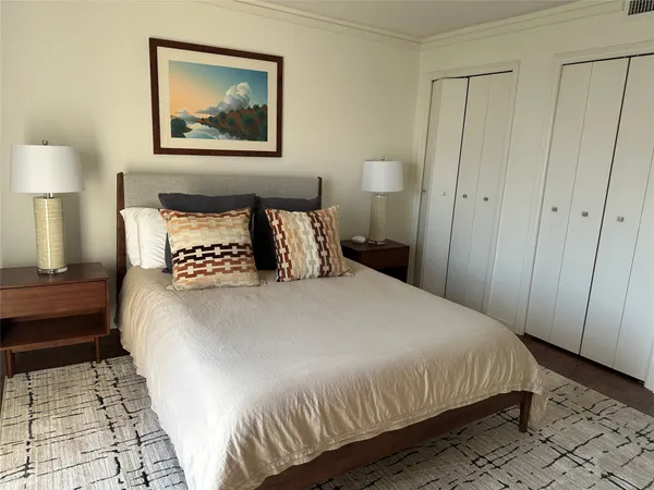 a bedroom with a bed and a lamp on dresser