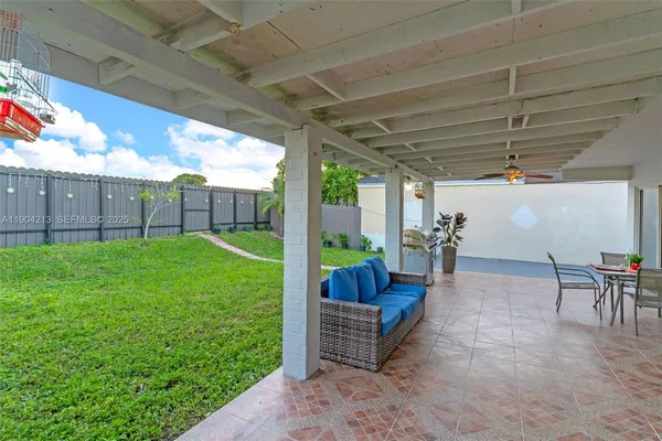 a view of a backyard with couches plants and wooden fence