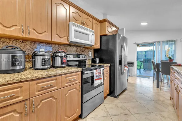 a kitchen with stainless steel appliances granite countertop a refrigerator a stove and a sink