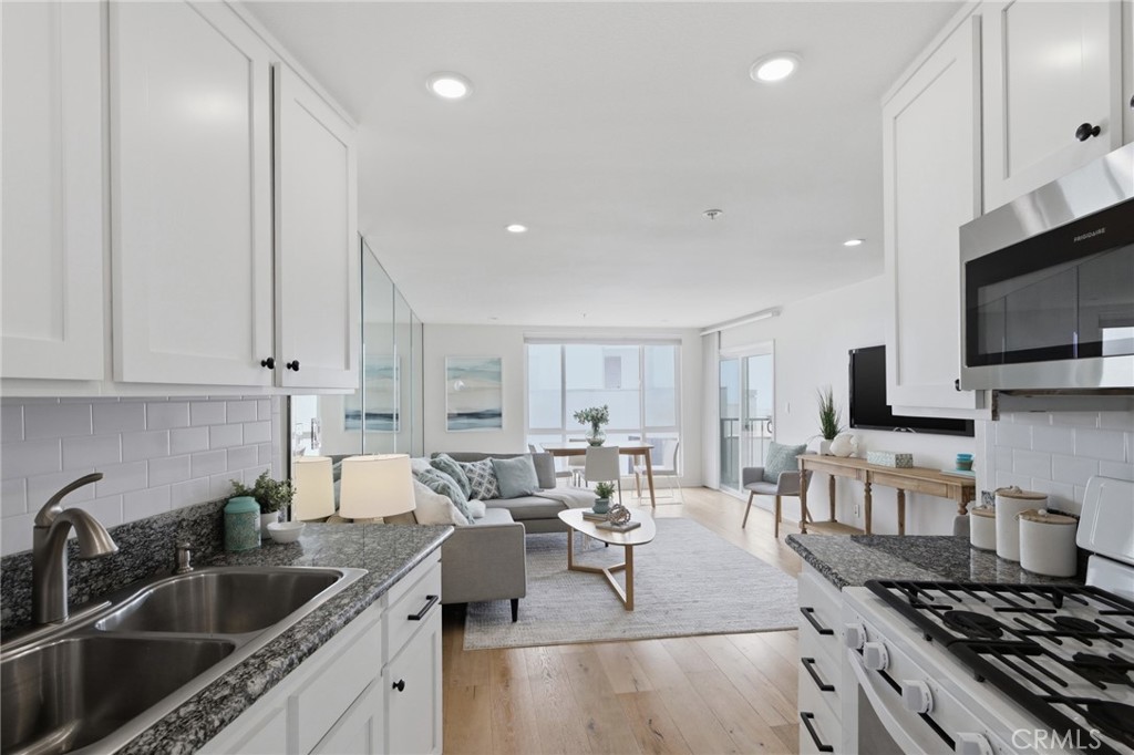 565 Esplanade, Unit 312 Redondo Beach, CA 90277 - Photo 11 of 32 a kitchen with stainless steel appliances granite countertop a sink dishwasher a stove and a microwave oven with white cabinets