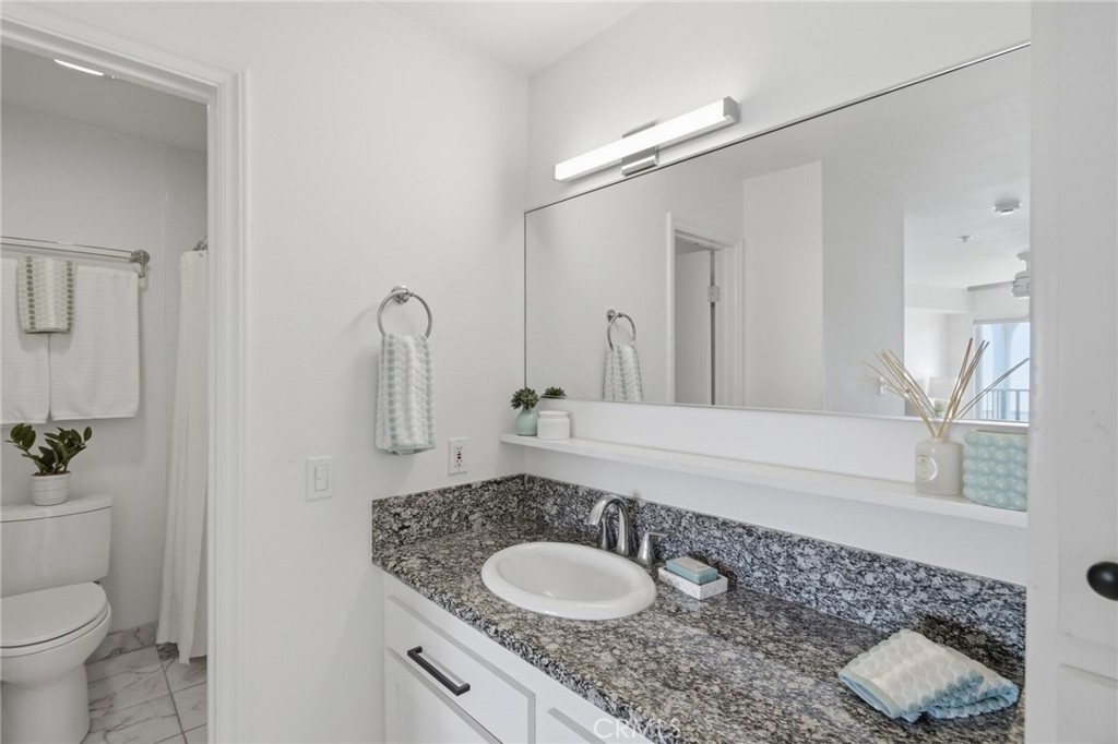 565 Esplanade, Unit 312 Redondo Beach, CA 90277 - Photo 20 of 32 a bathroom with a granite countertop sink a toilet and a mirror