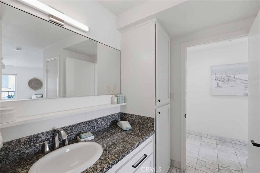 565 Esplanade, Unit 312 Redondo Beach, CA 90277 - Photo 23 of 32 a bathroom with a granite countertop sink and a mirror