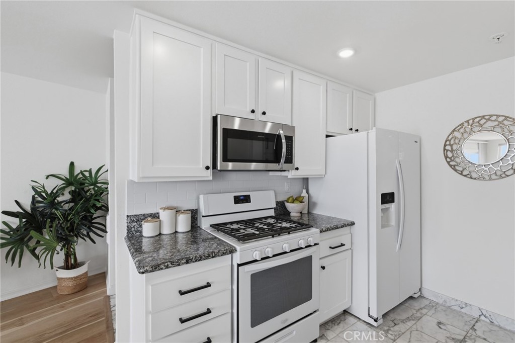 565 Esplanade, Unit 312 Redondo Beach, CA 90277 - Photo 7 of 32 a kitchen with granite countertop a stove and a white refrigerator