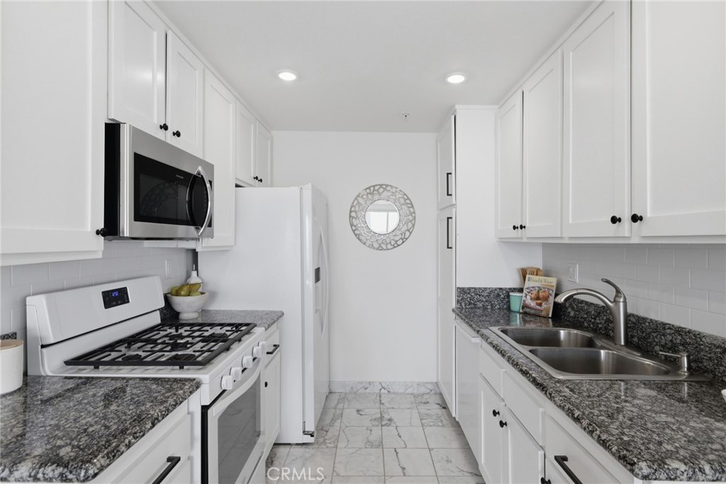 565 Esplanade, Unit 312 Redondo Beach, CA 90277 - Photo 8 of 32 a kitchen with granite countertop white cabinets and stainless steel appliances