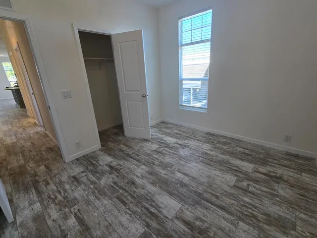 a view of an empty room with wooden floor and a window