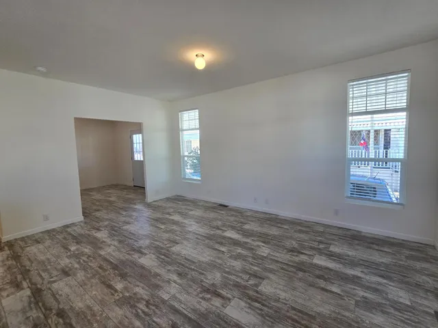 a view of an empty room with wooden floor and window