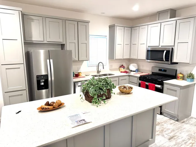 a kitchen with stainless steel appliances a sink a microwave a refrigerator and cabinets