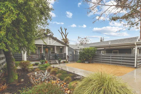 a front view of a house with a yard tree and wooden fence