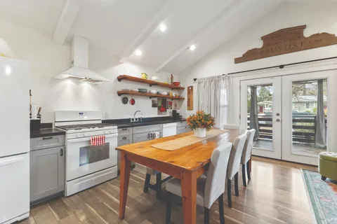 a kitchen with stainless steel appliances granite countertop a stove a table and chairs