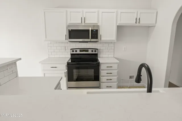 a kitchen with stainless steel appliances a stove a microwave and a sink