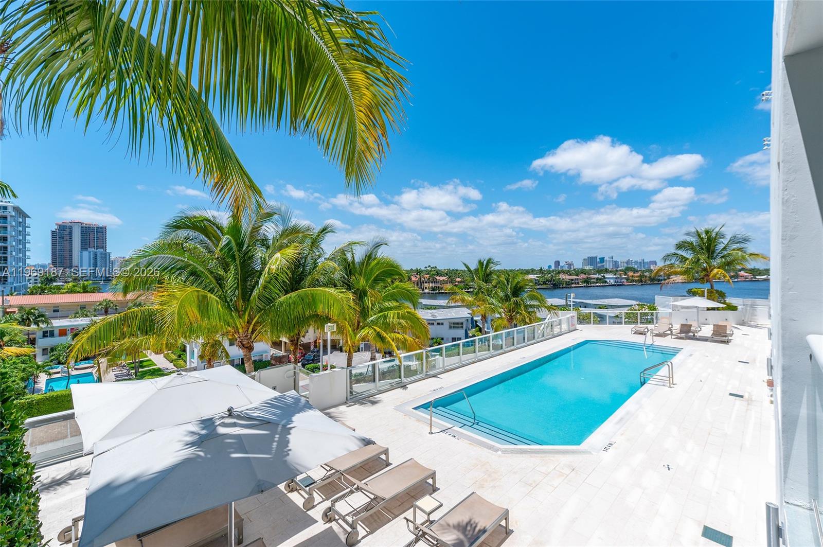 401 North Birch Road, Unit 502 Fort Lauderdale, FL 33304 - Photo 27 of 52 a view of a swimming pool with a lawn chairs under palm trees