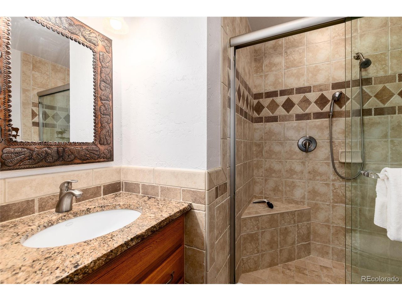 490 Kings Crossing Road, Unit 631 Winter Park, CO 80482 - Photo 28 of 43 a bathroom with a granite countertop sink a mirror and shower