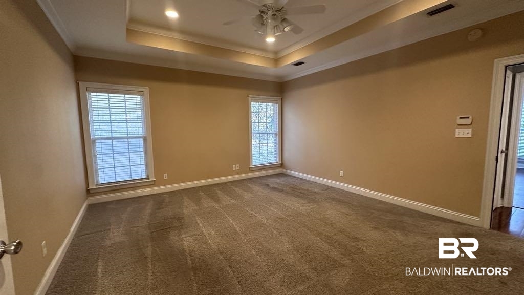23289 McPhillips Road Loxley, AL 36551 - Photo 8 of 19 Spacious room featuring neutral carpeting, two large windows with blinds, a tray ceiling with recessed lighting, and a ceiling fan