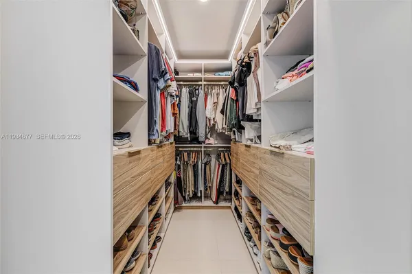 a view of walk in closet with clothes and shoes
