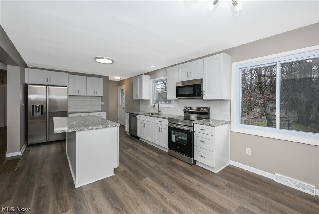 773 Bishop Road Cleveland, OH 44143 - Photo 11 of 34 Kitchen with appliances with stainless steel finishes, tasteful backsplash, dark wood-type flooring, and a kitchen island