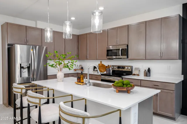 a kitchen with a sink a refrigerator and chairs