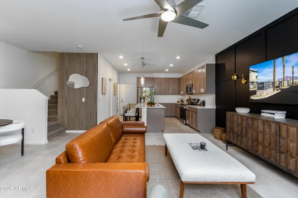 a living room with furniture kitchen view and a wooden floor