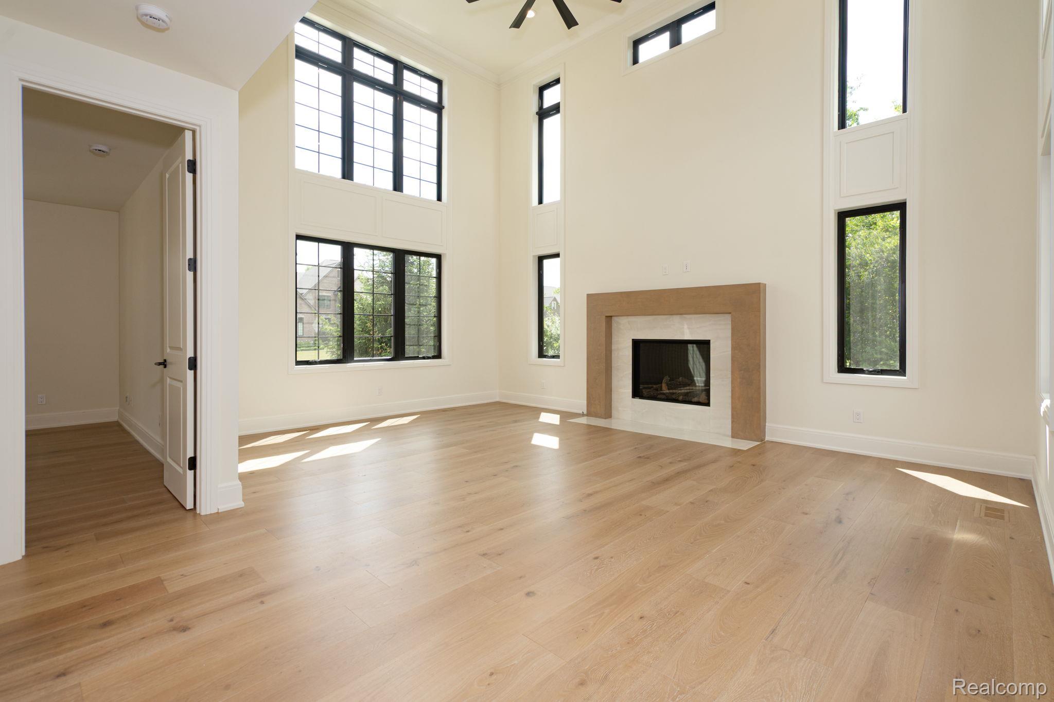 3836 Coachwood Lane Rochester, MI 48309 - Photo 49 of 82 Spacious room featuring high ceilings, wood-finish flooring, and a fireplace with a light-colored surround