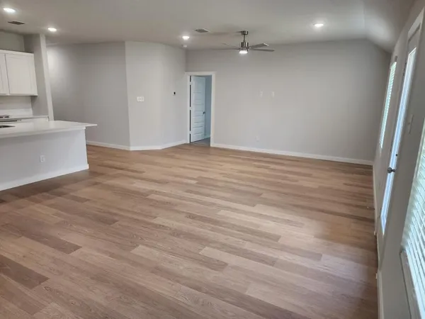 a view of an empty room with wooden floor and a window