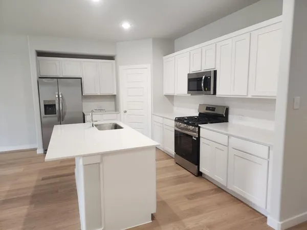 a kitchen with stainless steel appliances kitchen island granite countertop a sink a stove and cabinets