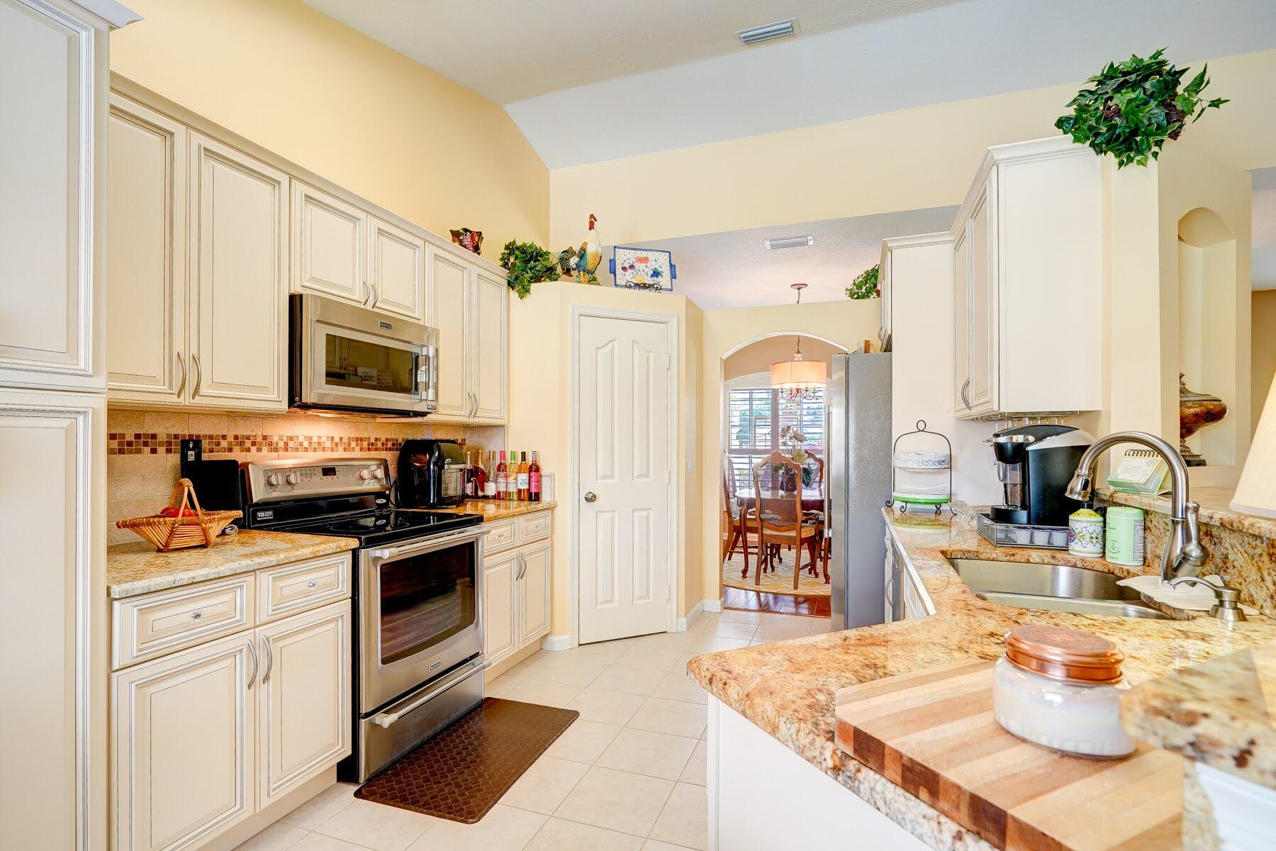 1829 Southwest Hickock Terrace Port St. Lucie, FL 34953 - Photo 28 of 62 a kitchen with stainless steel appliances granite countertop a sink dishwasher stove and refrigerator with wooden floor