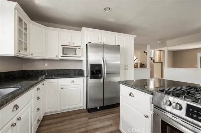 a kitchen with stainless steel appliances granite countertop a stove a refrigerator and a white cabinets