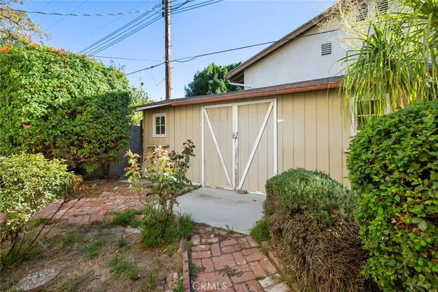 a backyard of a house with potted plants and large tree