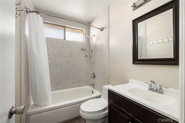 a bathroom with a bathtub shower sink vanity mirror and toilet