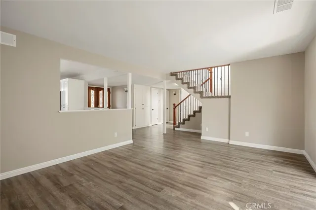 a view of an empty room with wooden floor and stairs
