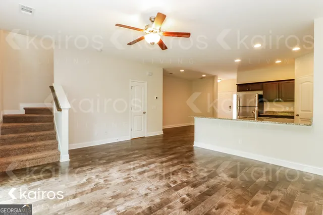 a view of kitchen and empty room with wooden floor