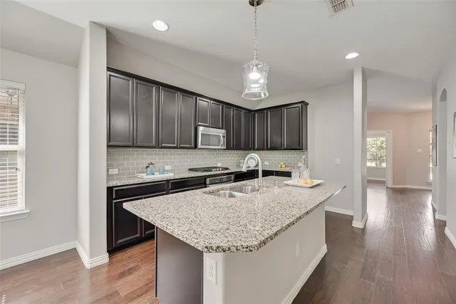 a kitchen with stainless steel appliances granite countertop a sink refrigerator and cabinets