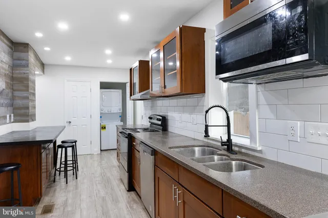 a kitchen with granite countertop a sink stainless steel appliances and cabinets