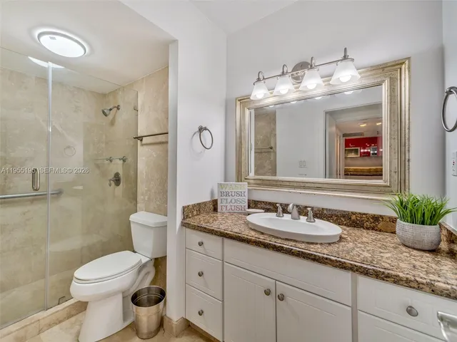 a bathroom with a granite countertop sink toilet a large mirror a shower and a mirror