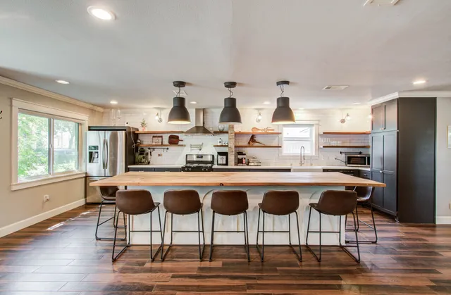 a kitchen with stainless steel appliances granite countertop a kitchen island a stove a table and chairs in it