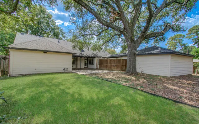 a backyard of a house with large trees and brick walls