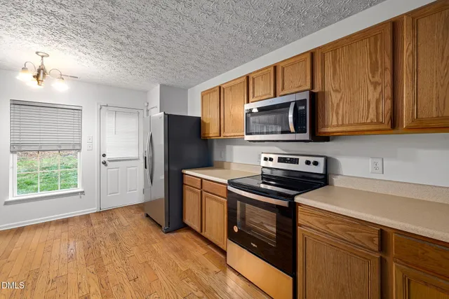 a kitchen with granite countertop wooden cabinets stainless steel appliances and a window