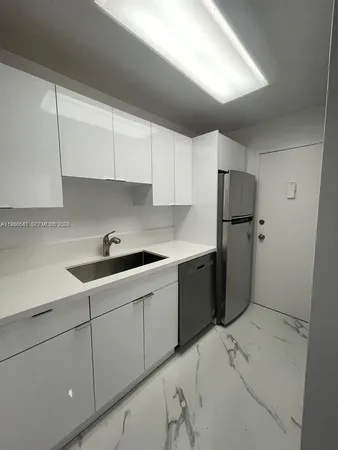a kitchen with a sink a refrigerator and cabinets